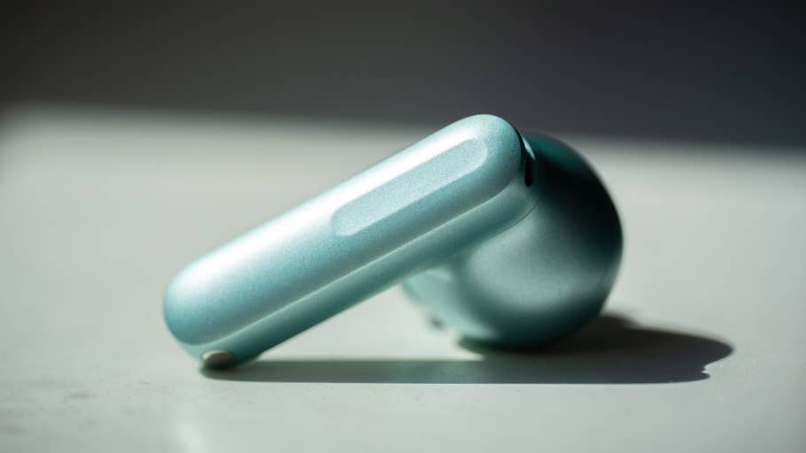 Eine Nahaufnahme der OnePlus Buds 4 in Teal auf einer weißen Oberfläche.