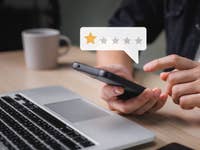 Smartphone in Händen vor Notebook