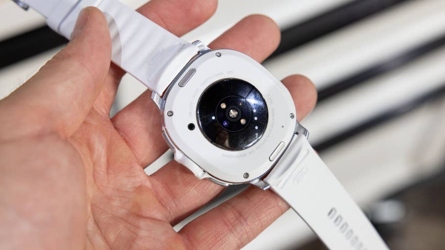 Eine Person hält die Rückansicht einer Samsung Galaxy Watch 8 Classic mit einem weißen Armband.