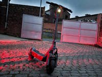 Ein Segway Ninebot der 3. Generation, der auf Kopfsteinpflaster mit rotem Licht in einer städtischen Umgebung geparkt ist.