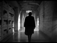 Schwarz-Weiß-Bild mit einer Silhouette eines Mannes mit Hut in einem Gang.
