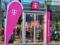 Eine Flagge mit dem Logo der Telekom steht vor einem Telekom-Shop