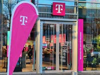 Eine Flagge mit dem Logo der Telekom steht vor einem Telekom-Shop