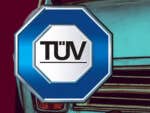 TÜV Logo vor einem alten Auto.
