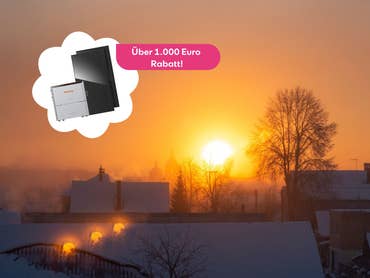 Ein Sonnenuntergang über verschneiten Dächern. Davor ist ein Set aus Stromspeichern und Solarpanels zu sehen.