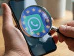 Eine Lupe mit EU-Sternen ist auf ein Smartphone mit großem WhatsApp-Logo gerichtet.