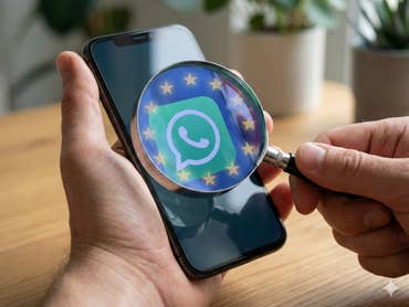 Eine Lupe mit EU-Sternen ist auf ein Smartphone mit großem WhatsApp-Logo gerichtet.