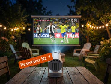 Ein Beamer wirft ein Fußballspiel zwischen Deutschland und Brasilien an eine Leinwand in einem Garten bei Nacht.